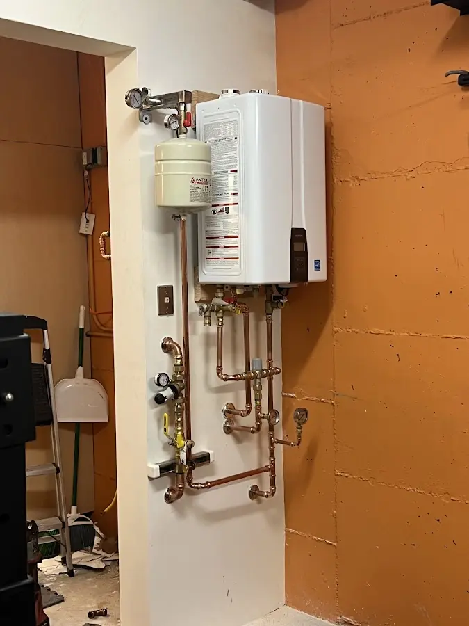 Plumbing technician inspecting water heater connections in Pittsfield
